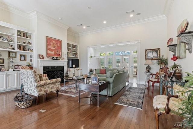 living room featuring built in features, crown molding, hardwood / wood-style floors, and a premium fireplace