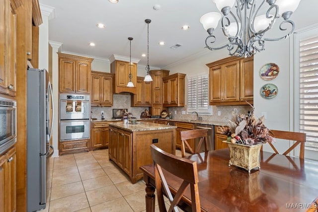 kitchen with light tile patterned floors, appliances with stainless steel finishes, brown cabinets, ornamental molding, and light stone countertops