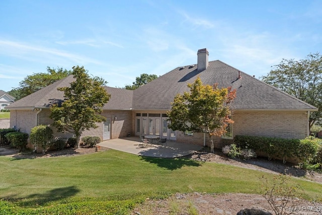 view of front of home featuring a front yard, a chimney, a patio, and brick siding