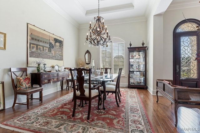 dining area featuring a tray ceiling, crown molding, wood finished floors, a chandelier, and baseboards