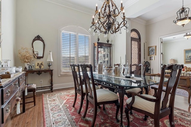 dining room with ornamental molding, a notable chandelier, baseboards, and wood finished floors