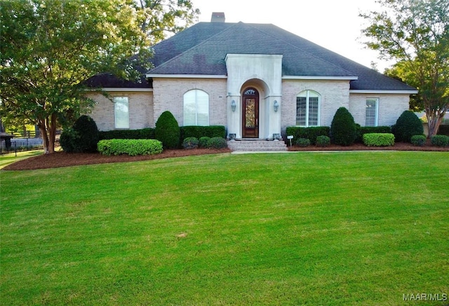 view of front of property with a shingled roof, a chimney, and a front yard