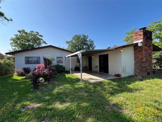 back of house with a carport and a yard