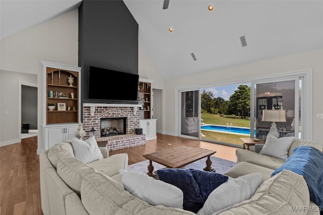 living room with high vaulted ceiling, hardwood / wood-style floors, and a brick fireplace