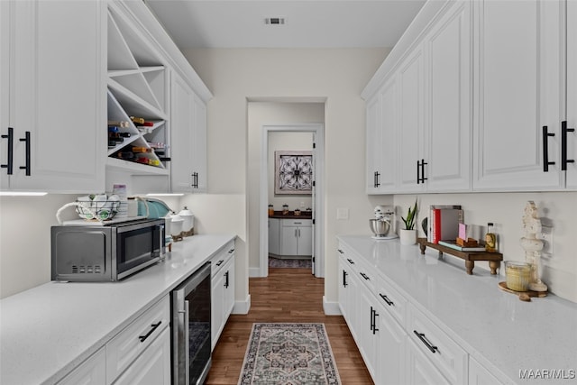 interior space featuring white cabinetry, beverage cooler, light stone counters, and dark hardwood / wood-style flooring