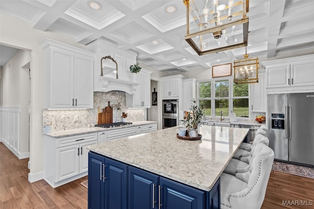 kitchen featuring coffered ceiling, stainless steel appliances, blue cabinetry, and tasteful backsplash