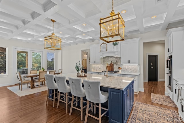 kitchen featuring beam ceiling, tasteful backsplash, blue cabinets, and coffered ceiling