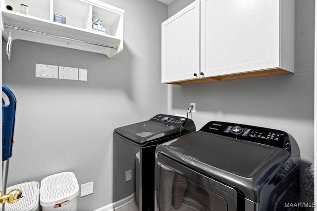 laundry area with separate washer and dryer and cabinets