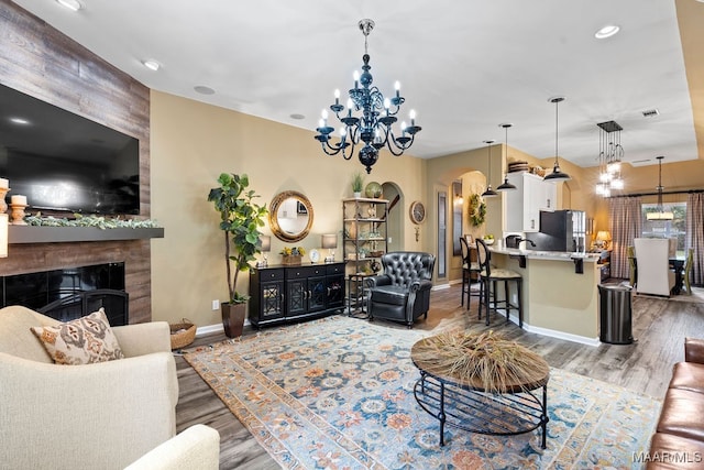 living room with an inviting chandelier, a tile fireplace, and wood-type flooring