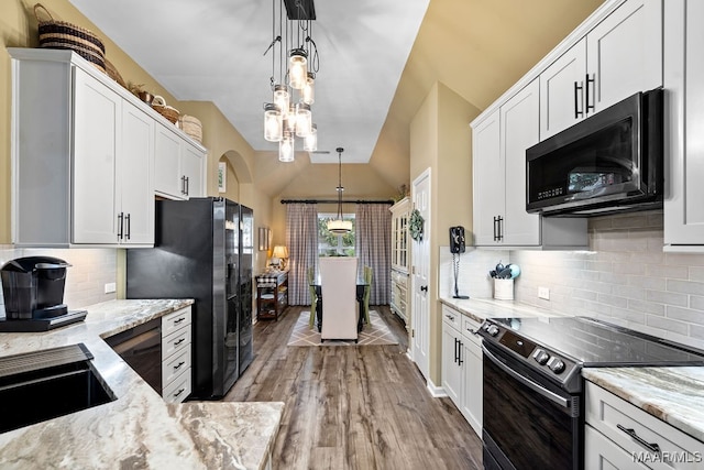 kitchen featuring backsplash, white cabinetry, black appliances, light wood-type flooring, and pendant lighting