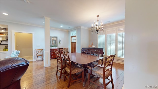 dining area with ornate columns, built in shelves, light hardwood / wood-style flooring, crown molding, and a chandelier