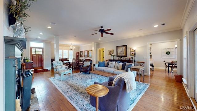 living room with hardwood / wood-style floors, ceiling fan with notable chandelier, and crown molding