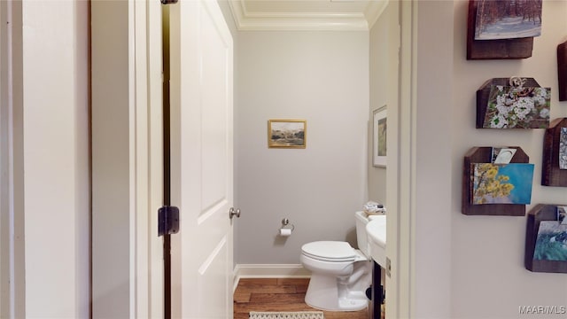 bathroom with hardwood / wood-style flooring, toilet, and crown molding