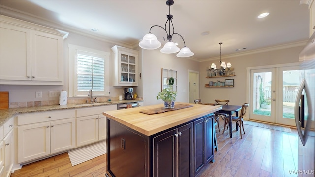 kitchen featuring a center island, white cabinets, sink, butcher block countertops, and a notable chandelier