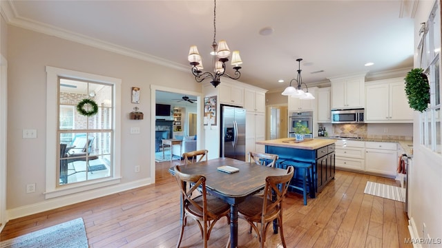 dining space with crown molding, light hardwood / wood-style floors, and ceiling fan with notable chandelier