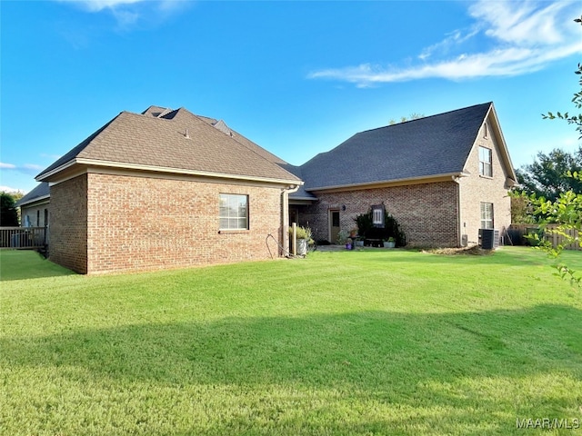 back of house with central AC unit and a yard