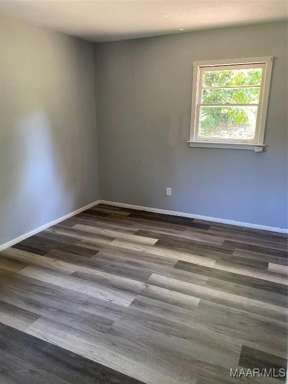 empty room with dark wood finished floors and baseboards