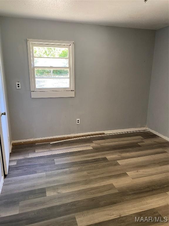 spare room featuring a textured ceiling, baseboards, and wood finished floors