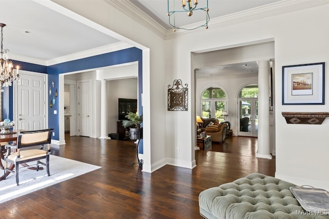 entryway with ornamental molding, dark wood-type flooring, ornate columns, and a notable chandelier