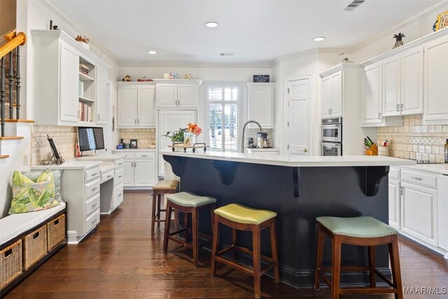 kitchen with dark wood-type flooring, decorative backsplash, crown molding, and white cabinetry