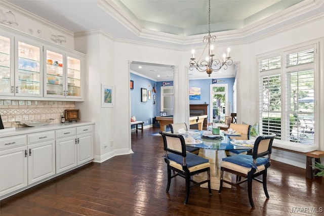 dining space with a tray ceiling, a chandelier, dark hardwood / wood-style flooring, and ornamental molding