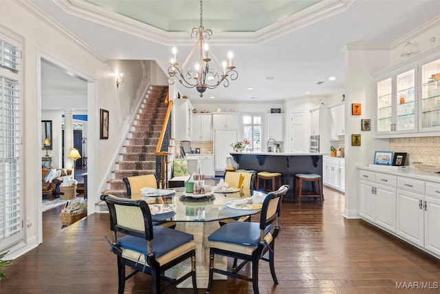 dining room with crown molding, a raised ceiling, and dark hardwood / wood-style flooring