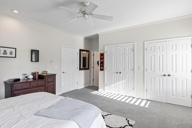 bedroom with ceiling fan, carpet, crown molding, and multiple closets