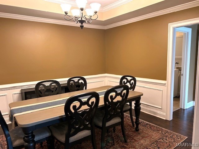 dining room featuring a tray ceiling, dark hardwood / wood-style floors, a chandelier, and ornamental molding