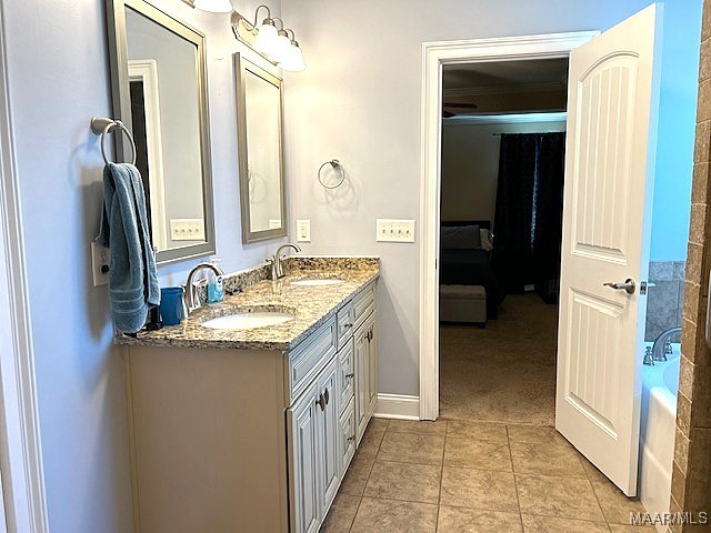 bathroom with a tub to relax in, vanity, and tile patterned flooring