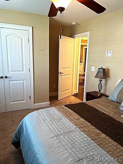 carpeted bedroom featuring ceiling fan and a closet