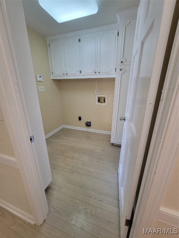 laundry area featuring hookup for a washing machine, light hardwood / wood-style flooring, and cabinets