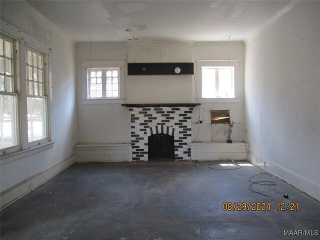 unfurnished living room featuring concrete flooring, a fireplace, crown molding, and baseboards