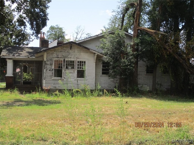 exterior space featuring a lawn, a chimney, and a sunroom