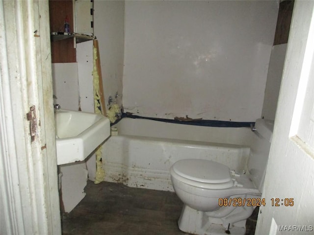 bathroom featuring concrete floors, toilet, and a tub to relax in