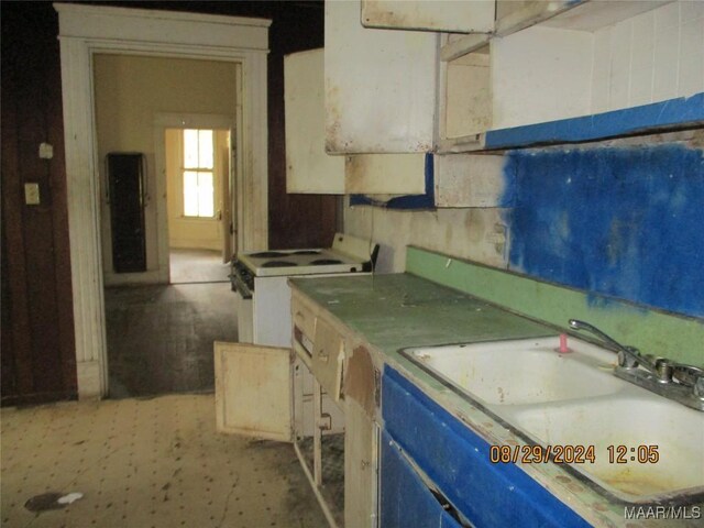 kitchen with white electric range, blue cabinetry, and a sink