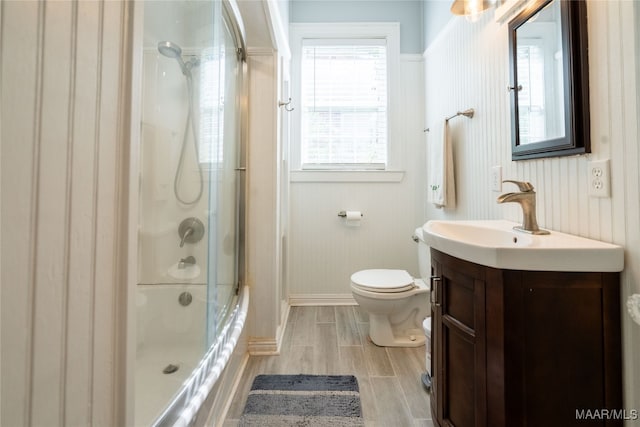 full bathroom featuring vanity, toilet, wood-type flooring, and shower / bath combination with glass door