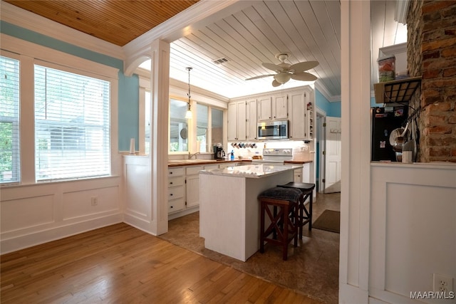 kitchen with hanging light fixtures, range with electric stovetop, a breakfast bar area, light hardwood / wood-style flooring, and a center island