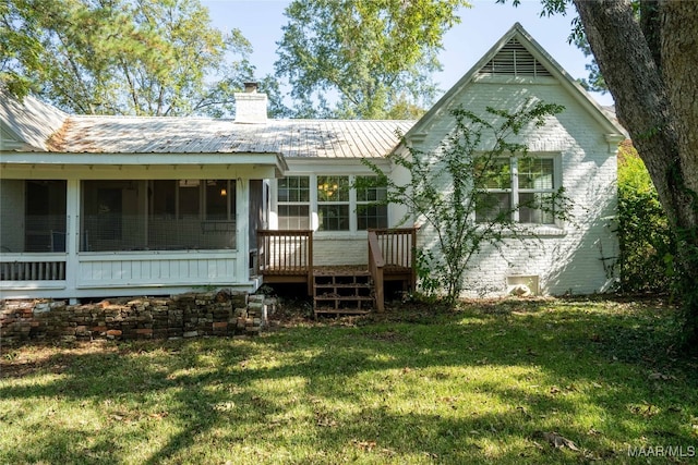 back of property featuring a sunroom and a lawn