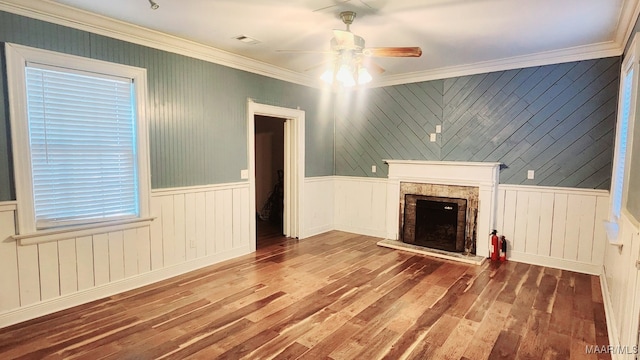 unfurnished living room featuring wood walls, ornamental molding, hardwood / wood-style flooring, and ceiling fan