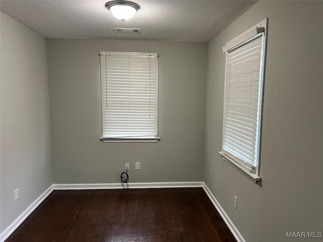 unfurnished room featuring dark hardwood / wood-style flooring and a textured ceiling