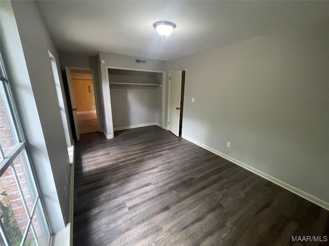 unfurnished bedroom with dark hardwood / wood-style floors and a closet