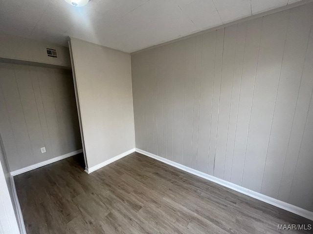 spare room with wood walls and dark hardwood / wood-style flooring