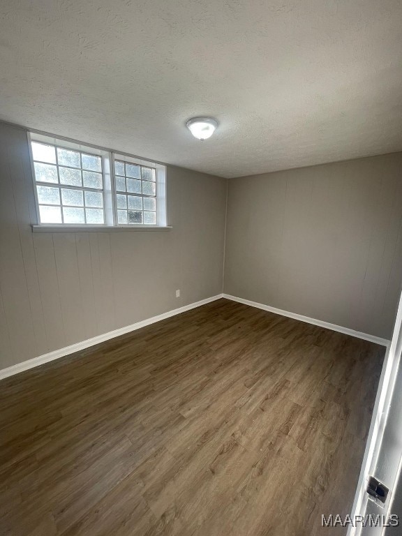 empty room with a textured ceiling and dark hardwood / wood-style flooring