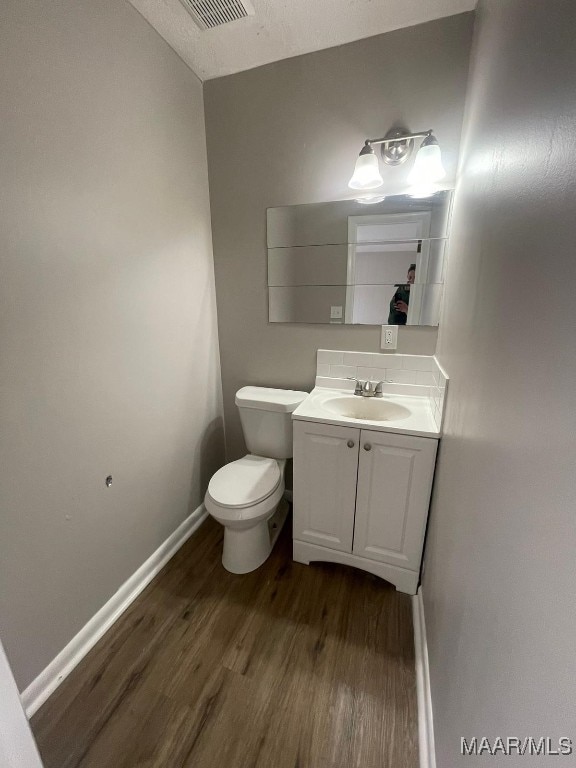 bathroom with toilet, vanity, a textured ceiling, vaulted ceiling, and hardwood / wood-style flooring