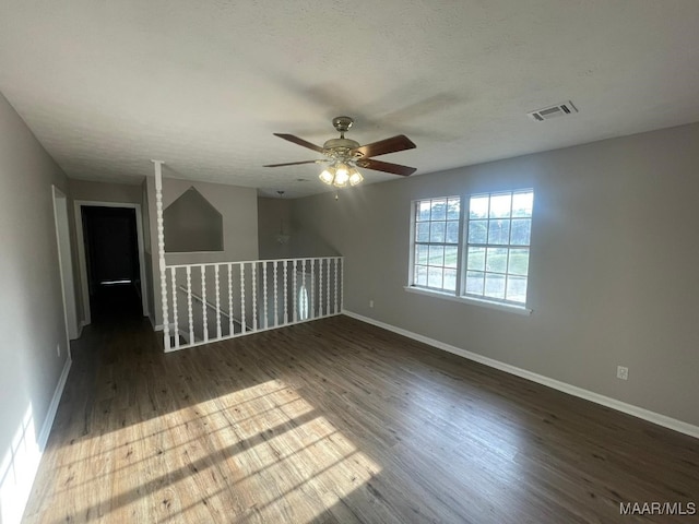 spare room with a textured ceiling, ceiling fan, and dark hardwood / wood-style floors