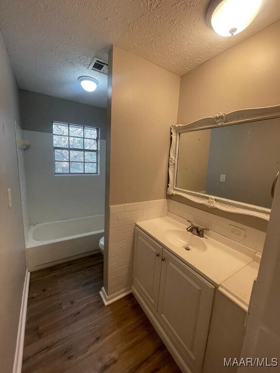 14 Azaleawood Dr, Wetumpka, AL 36093 - full bath with wood finished floors, toilet, vanity, a textured ceiling, and shower / tub combination