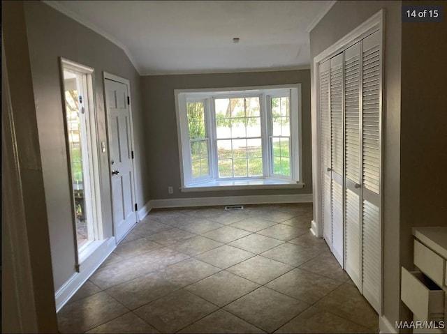 interior space featuring ornamental molding, vaulted ceiling, and tile patterned floors