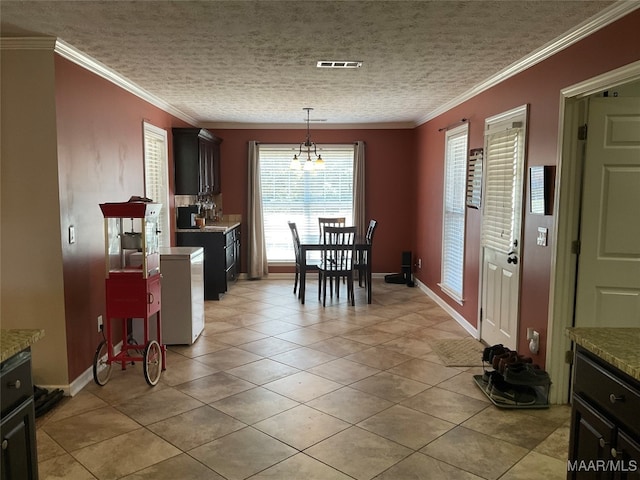 tiled dining space with crown molding, a textured ceiling, and a notable chandelier