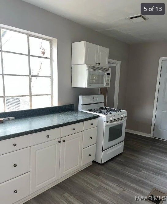 kitchen with white cabinets, plenty of natural light, dark hardwood / wood-style flooring, and white appliances