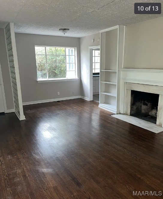 unfurnished living room featuring a textured ceiling, a premium fireplace, and dark hardwood / wood-style flooring